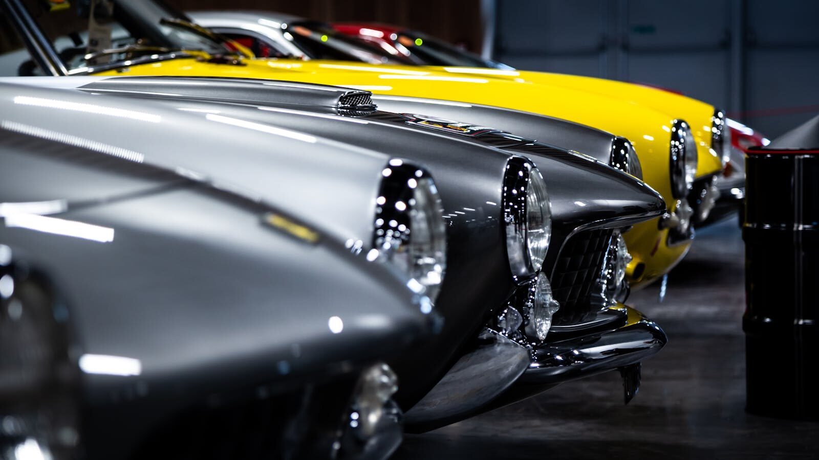 Photo by Quentin Martinez A close-up view of classic vintage cars lined up in an indoor showroom.